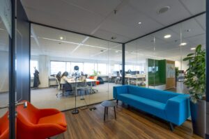 Moderne kantoorruimte aan de Johan Huizingalaan met een wachtruimte en uitzicht op een gedeelde werkplek achter glazen wanden.